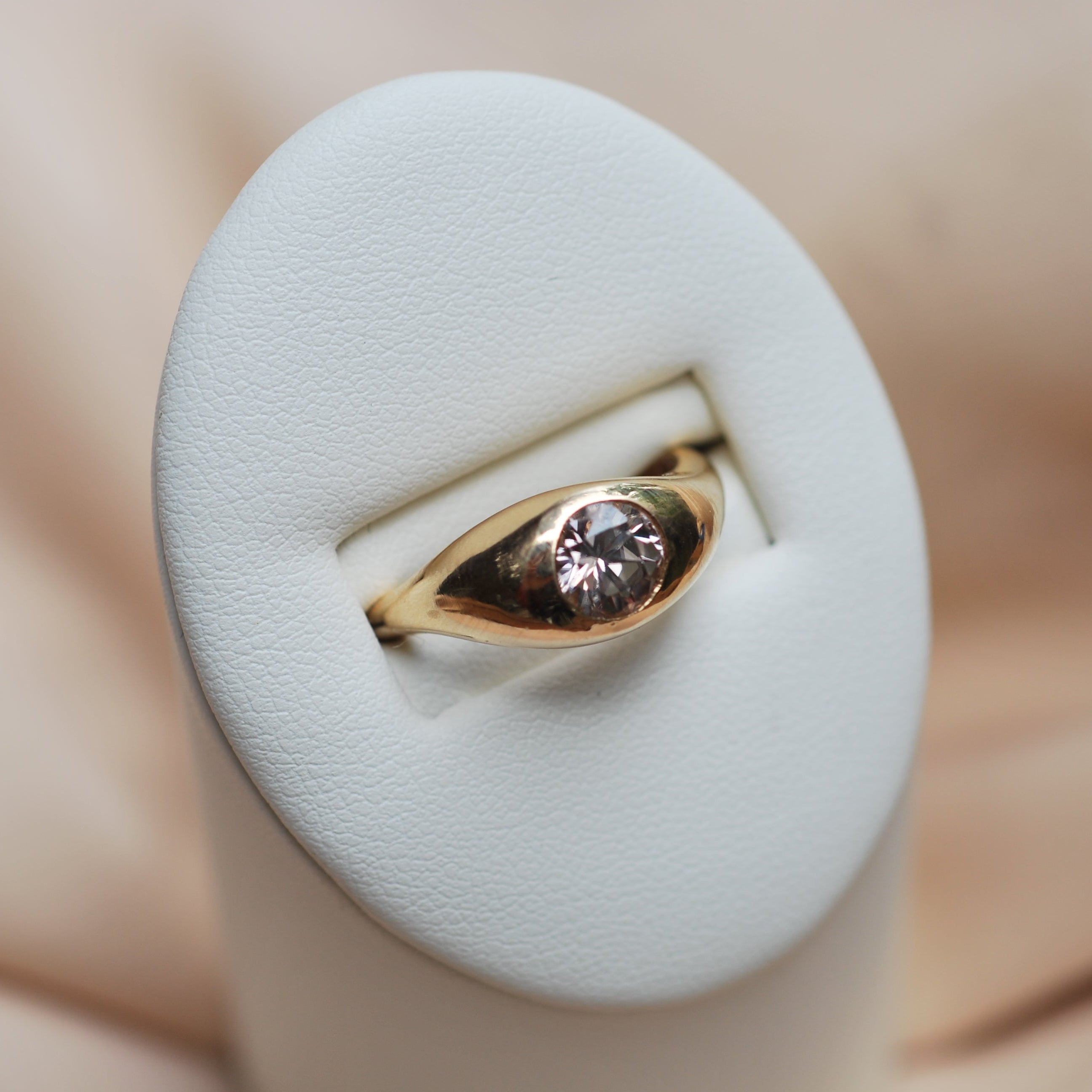 Gold ring with a champagne colored zircon on a white cushion