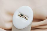 Gold ring with a blue gemstone in a white ring box on a beige background