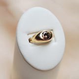 Gold ring with a zircon stone on a white stone surface