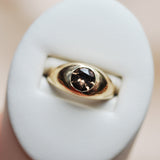 Close up of a gold ring with a brown faceted flush set stone