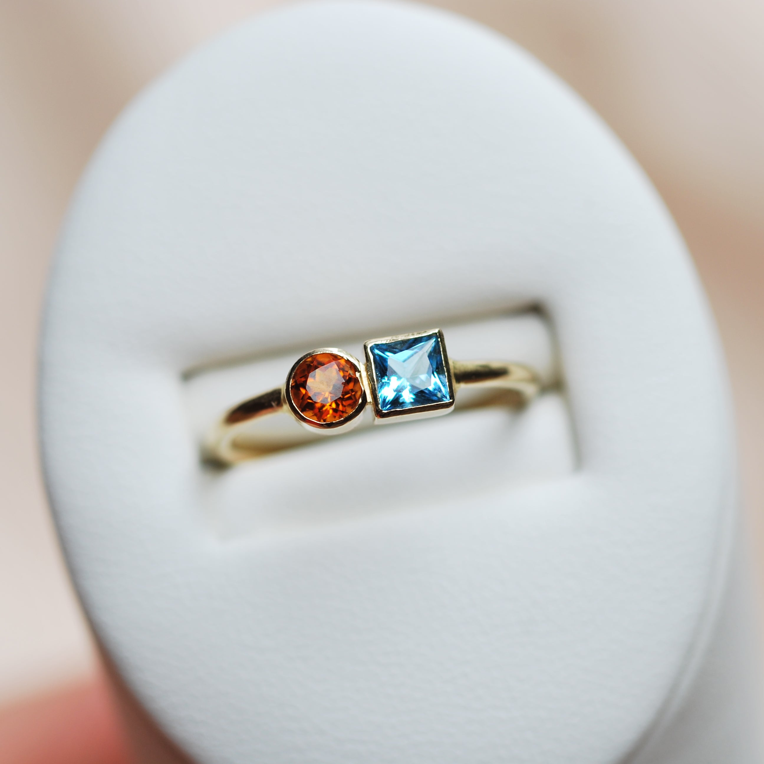 Gold ring with a blue square aquamarine gemstone and a round orange citrine gemstone