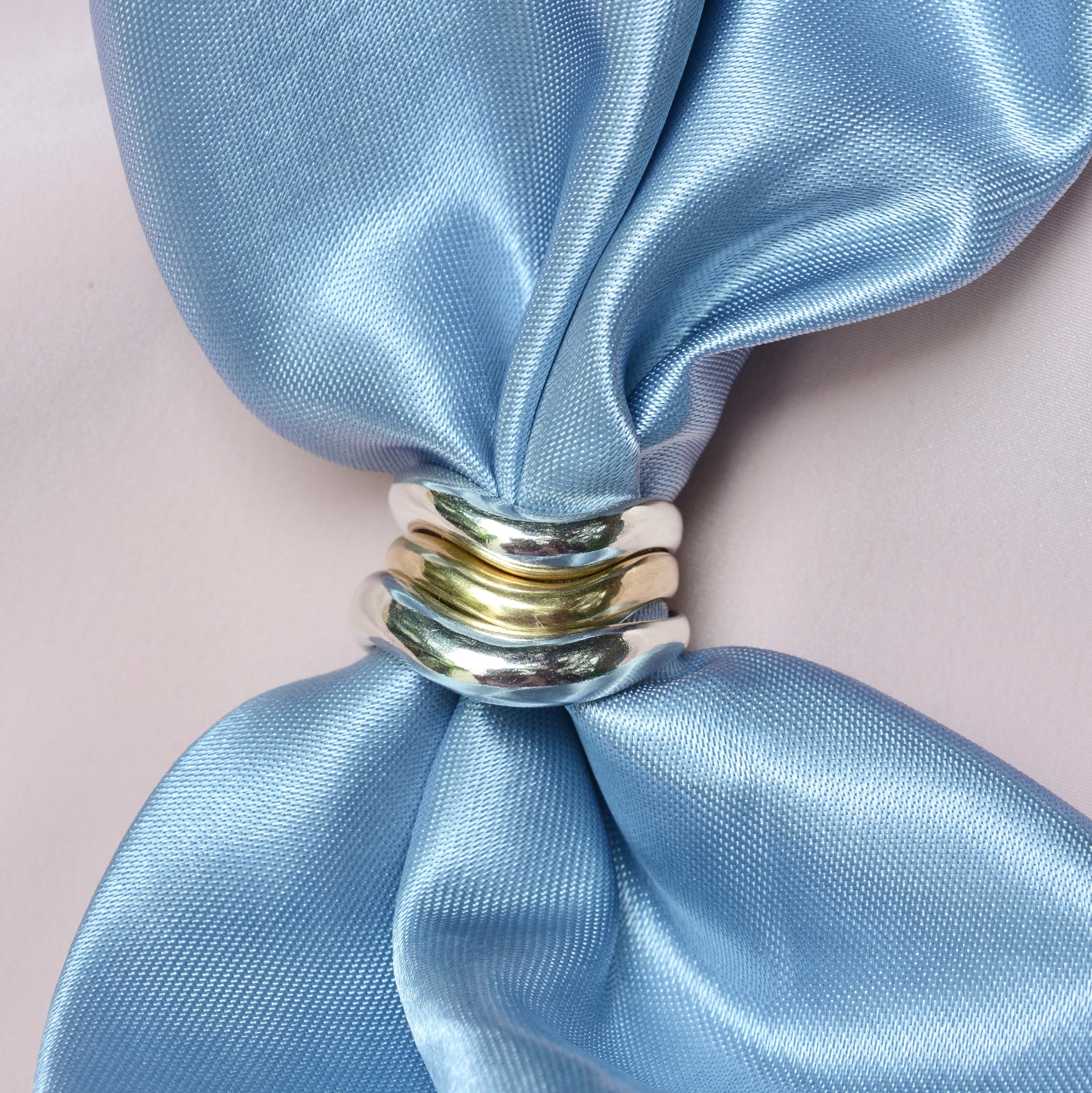 Silver and bronze narrow organic rings on a blue satin fabric