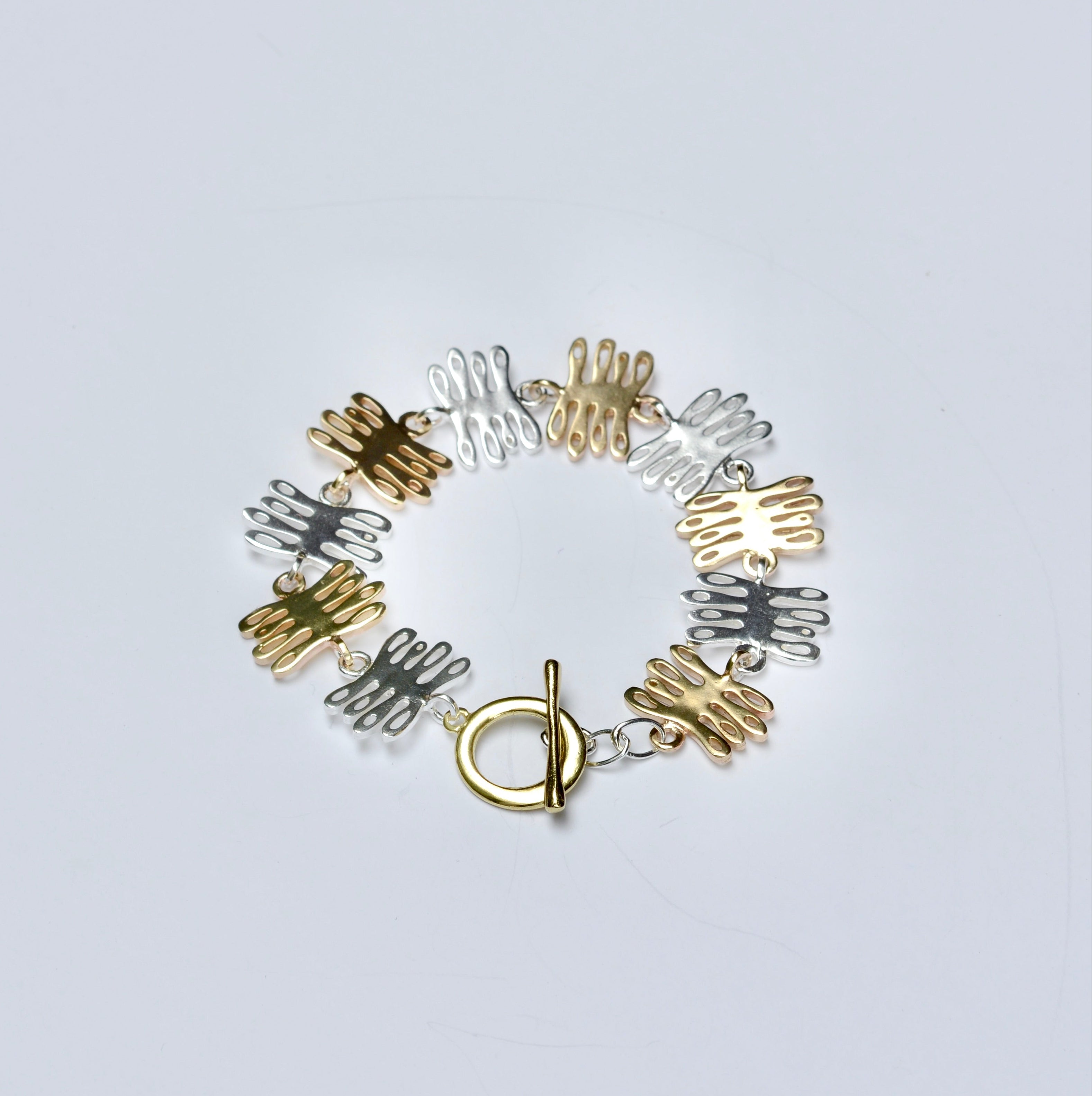 Bronze and silver bracelet with coral shaped charms on a light gray background