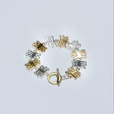 Bronze and silver bracelet with coral shaped charms on a light gray background