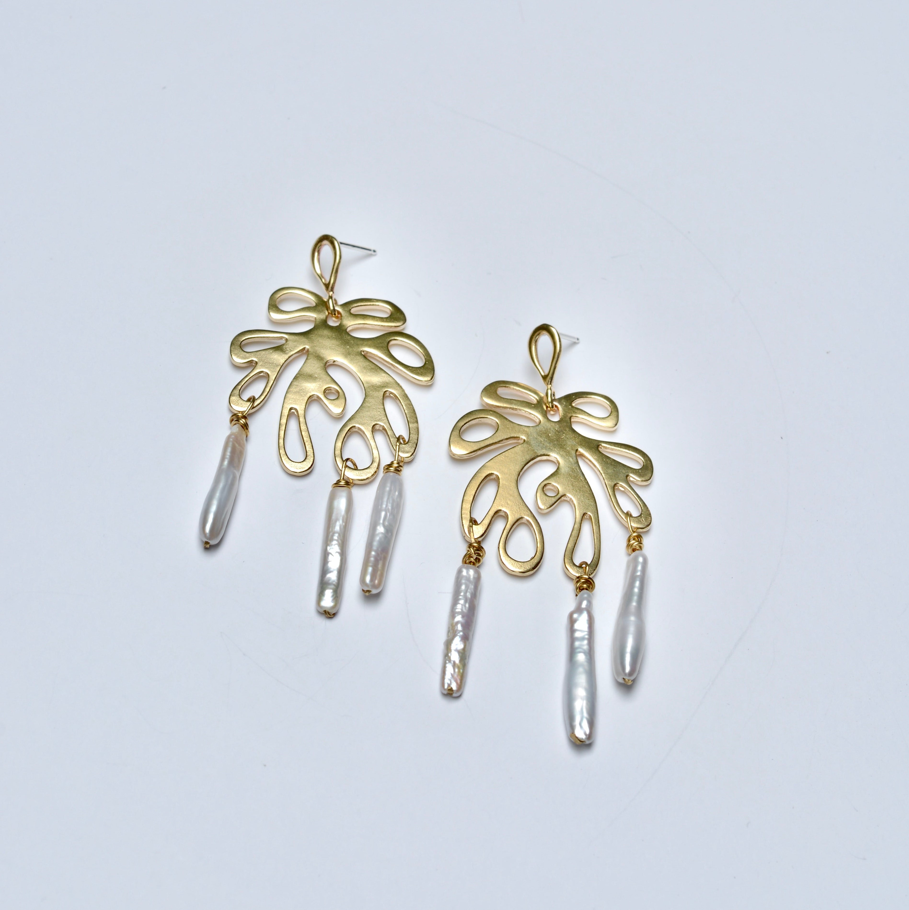 Bronze leaf earrings with pearl dangles on a light gray background