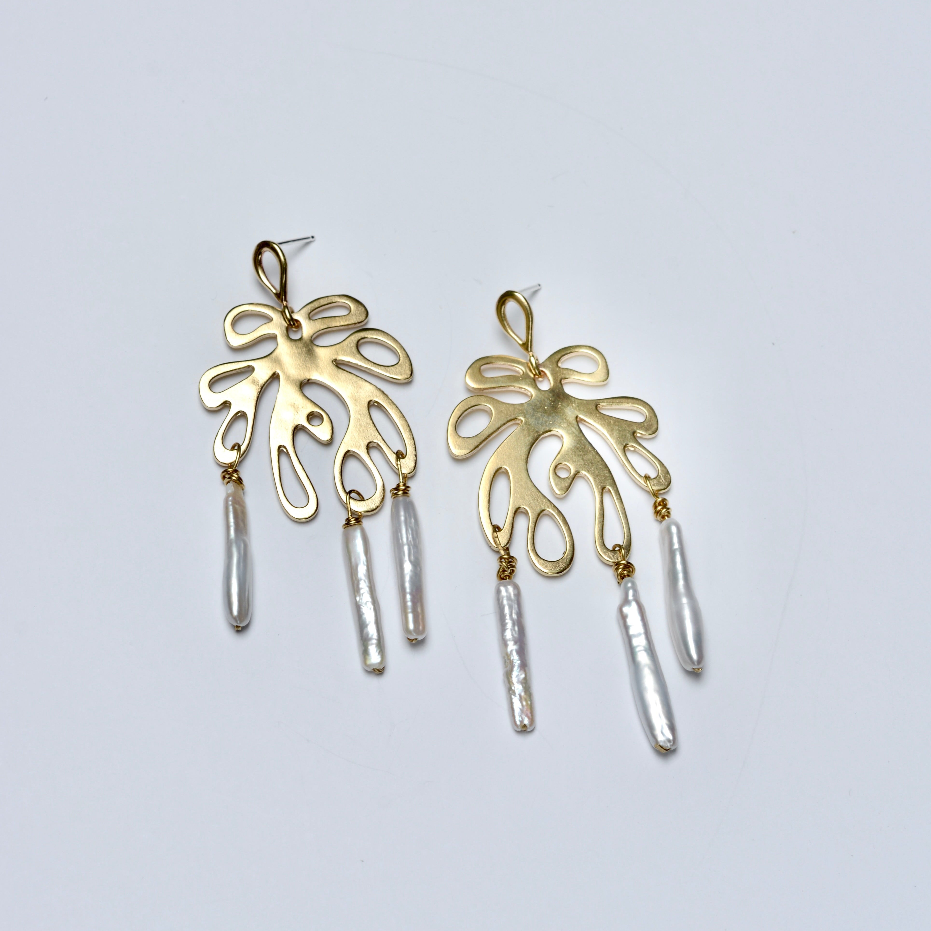 Bronze earrings with leaf-like shapes and cylindrical pearls on a light gray background