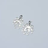 Pair of silver leaf-shaped earrings on a light gray background