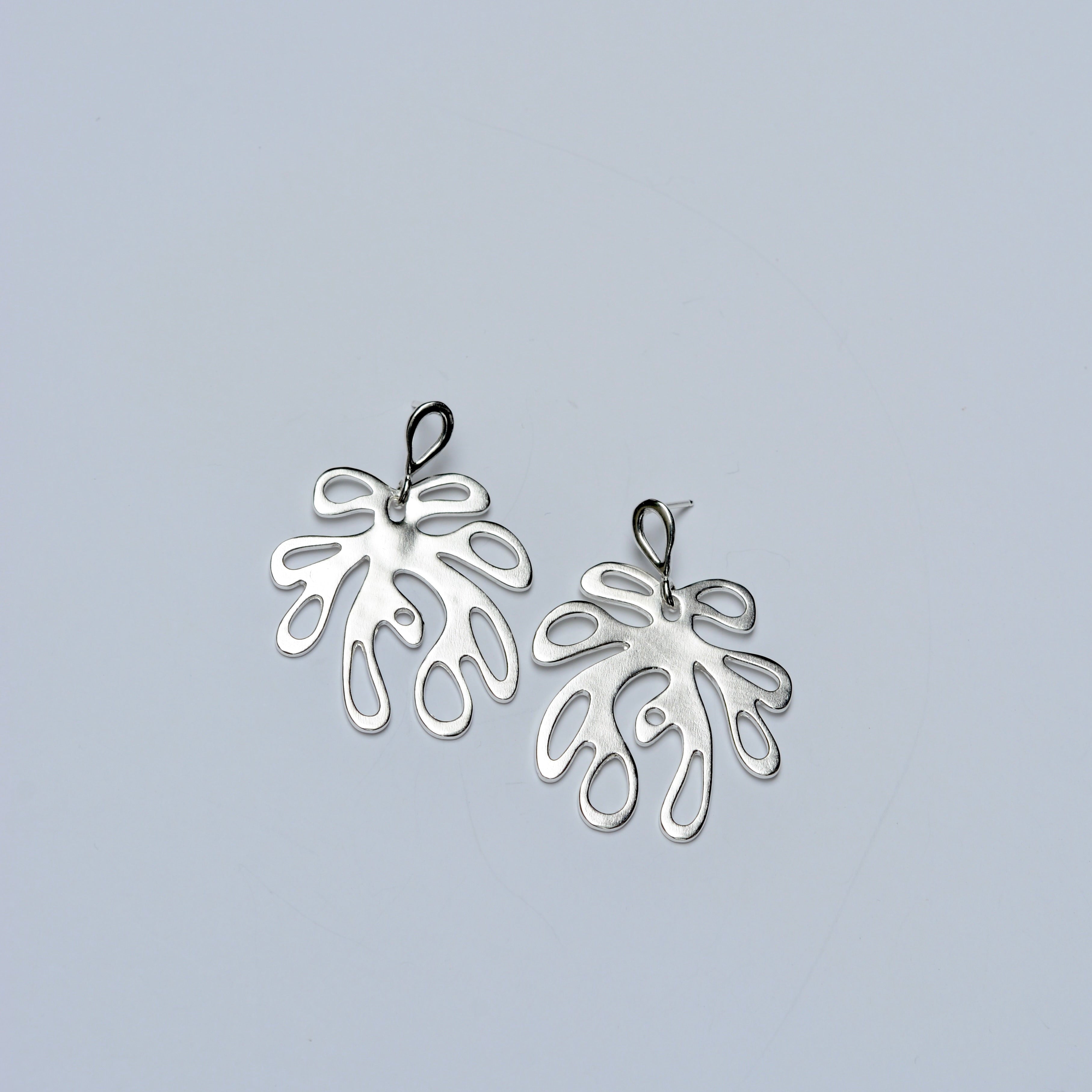 Pair of silver coral shaped earrings on a light gray background