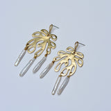 Gold coral earrings with pearl drops on a light gray background