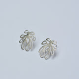 Pair of silver leaf-shaped earrings on a light gray background