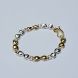 Bracelet with gold and silver mask shaped links on a light gray background
