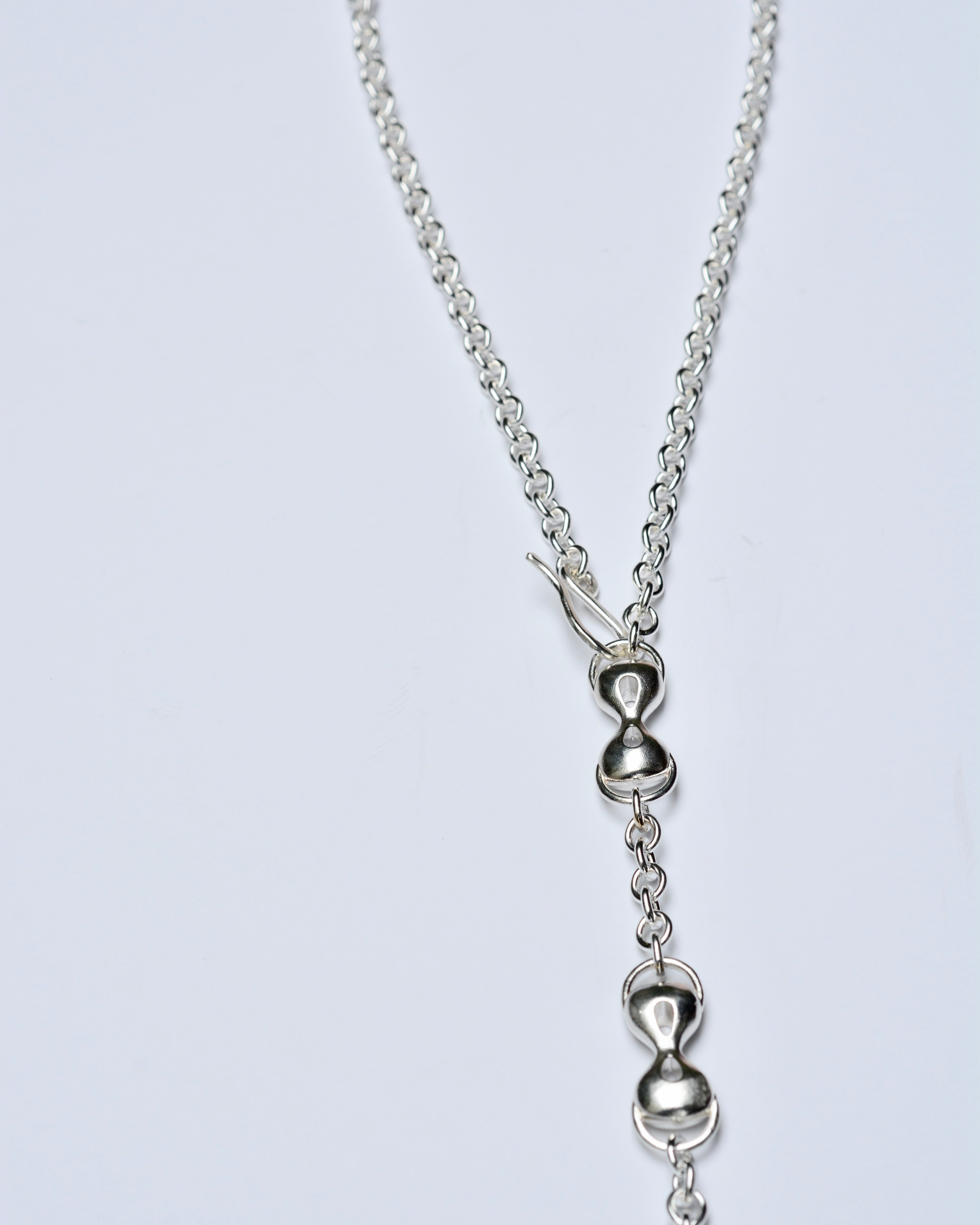 Silver necklace with a unique pendant on a light gray background