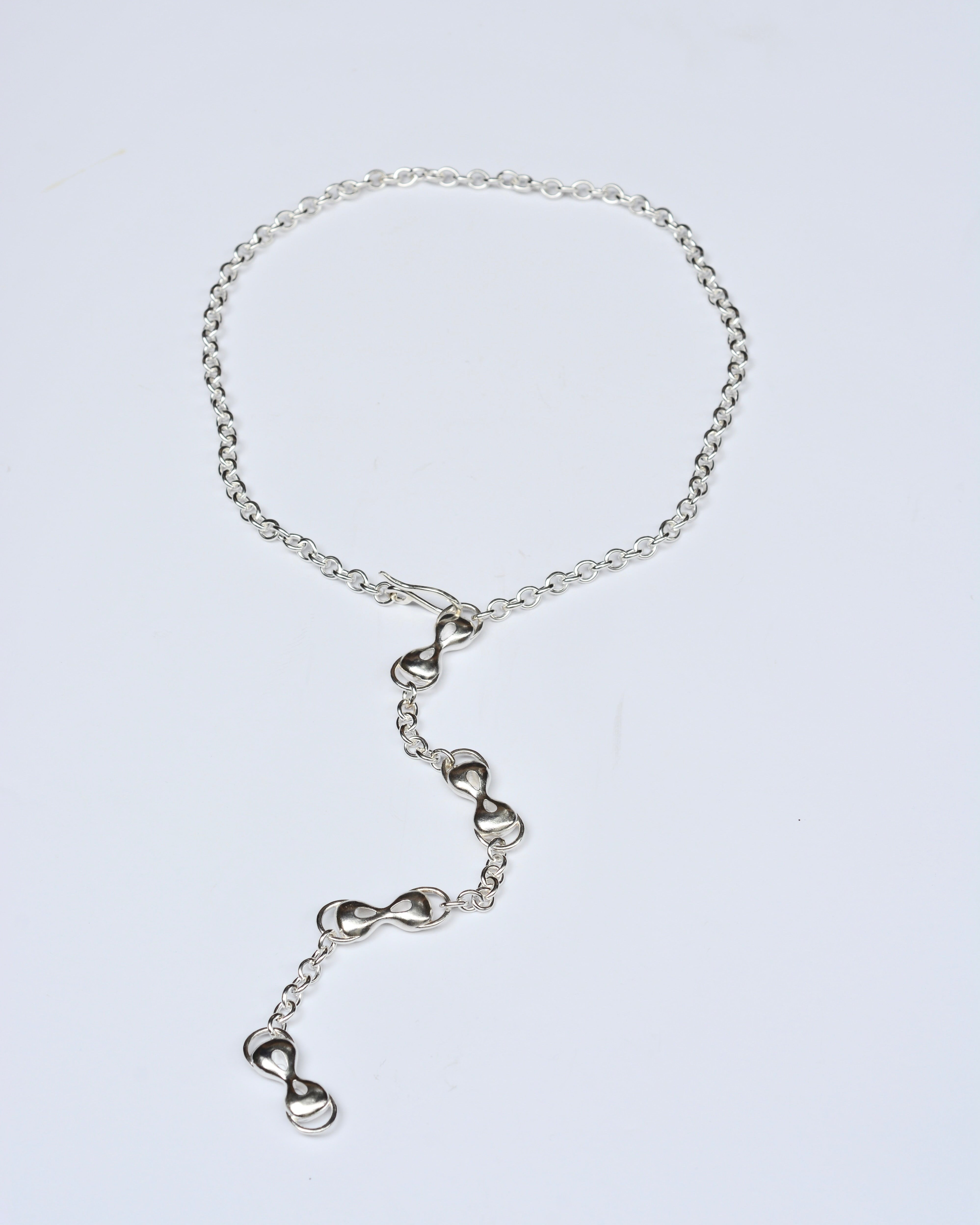 Silver chain necklace on a light gray background