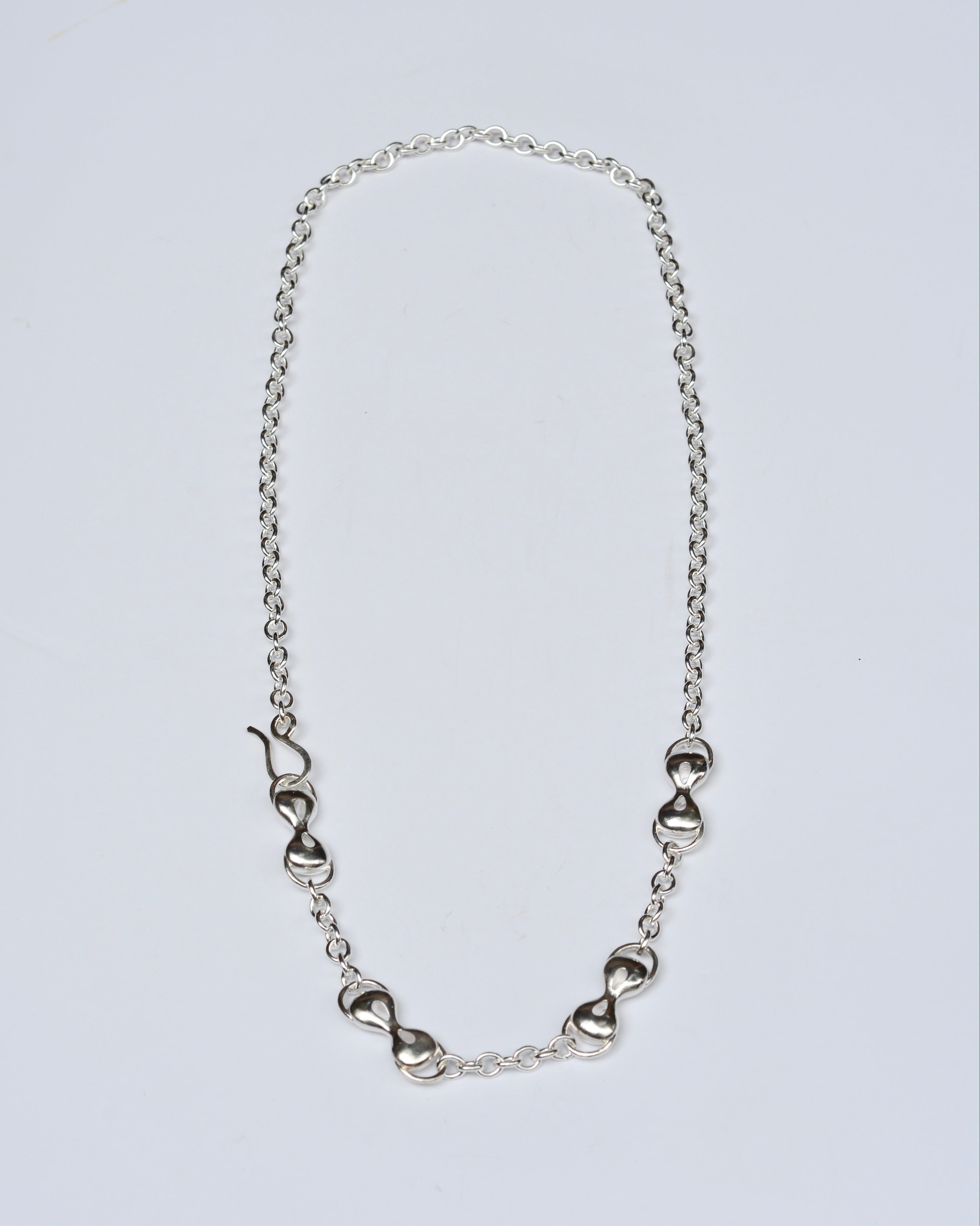 Silver necklace with infinity-shaped links on a light gray background