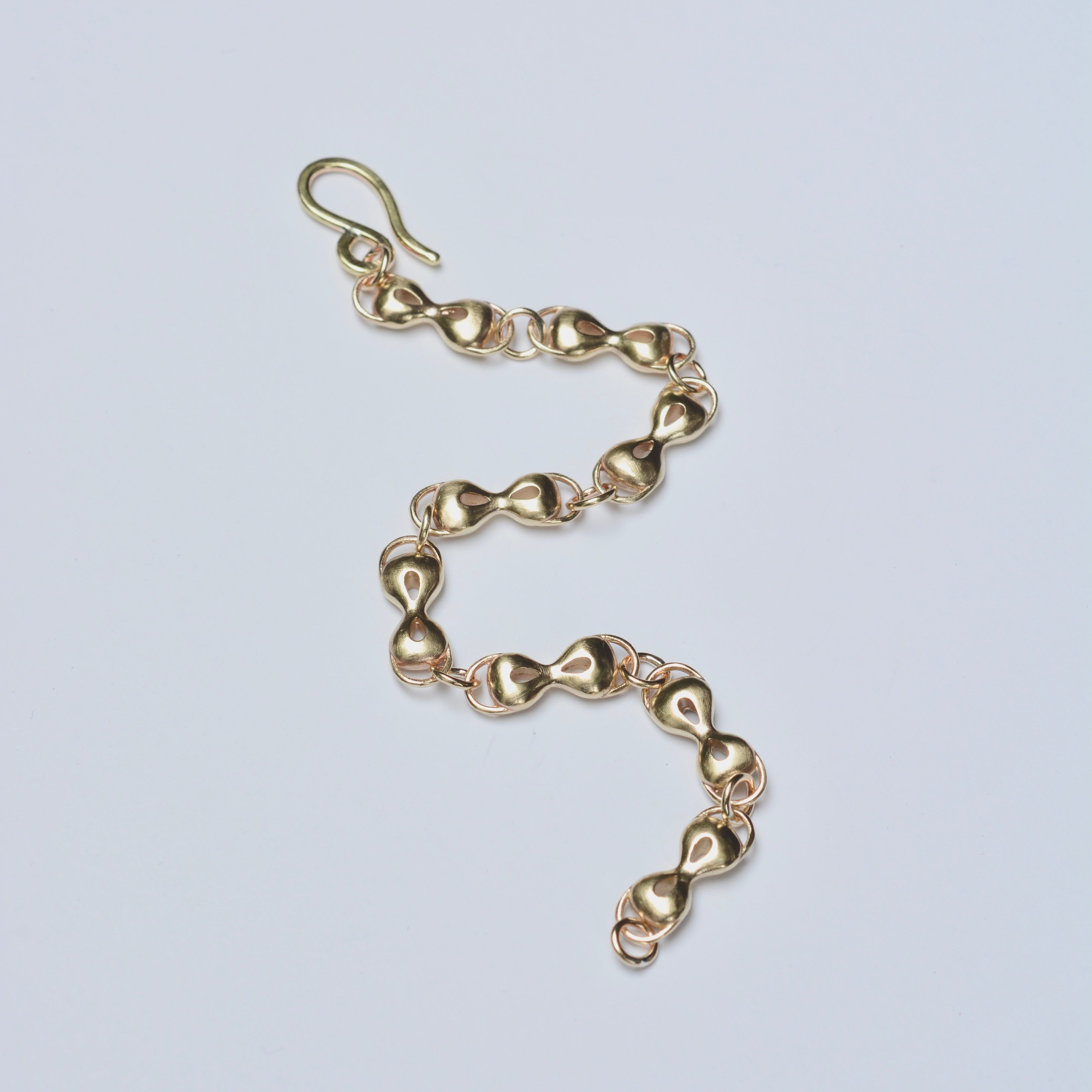 Gold chain bracelet on a light gray background