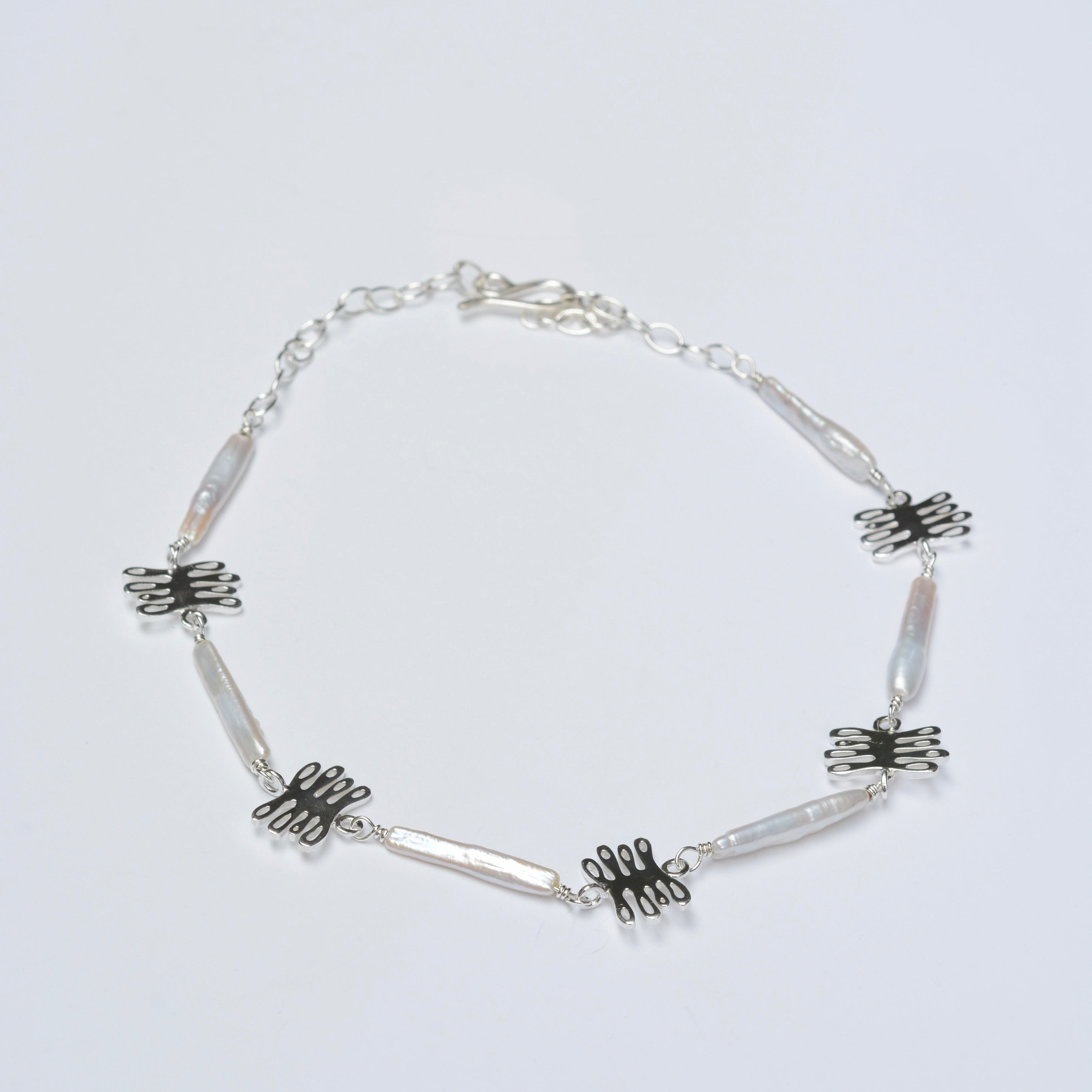 Silver necklace with coral charms on a light gray background