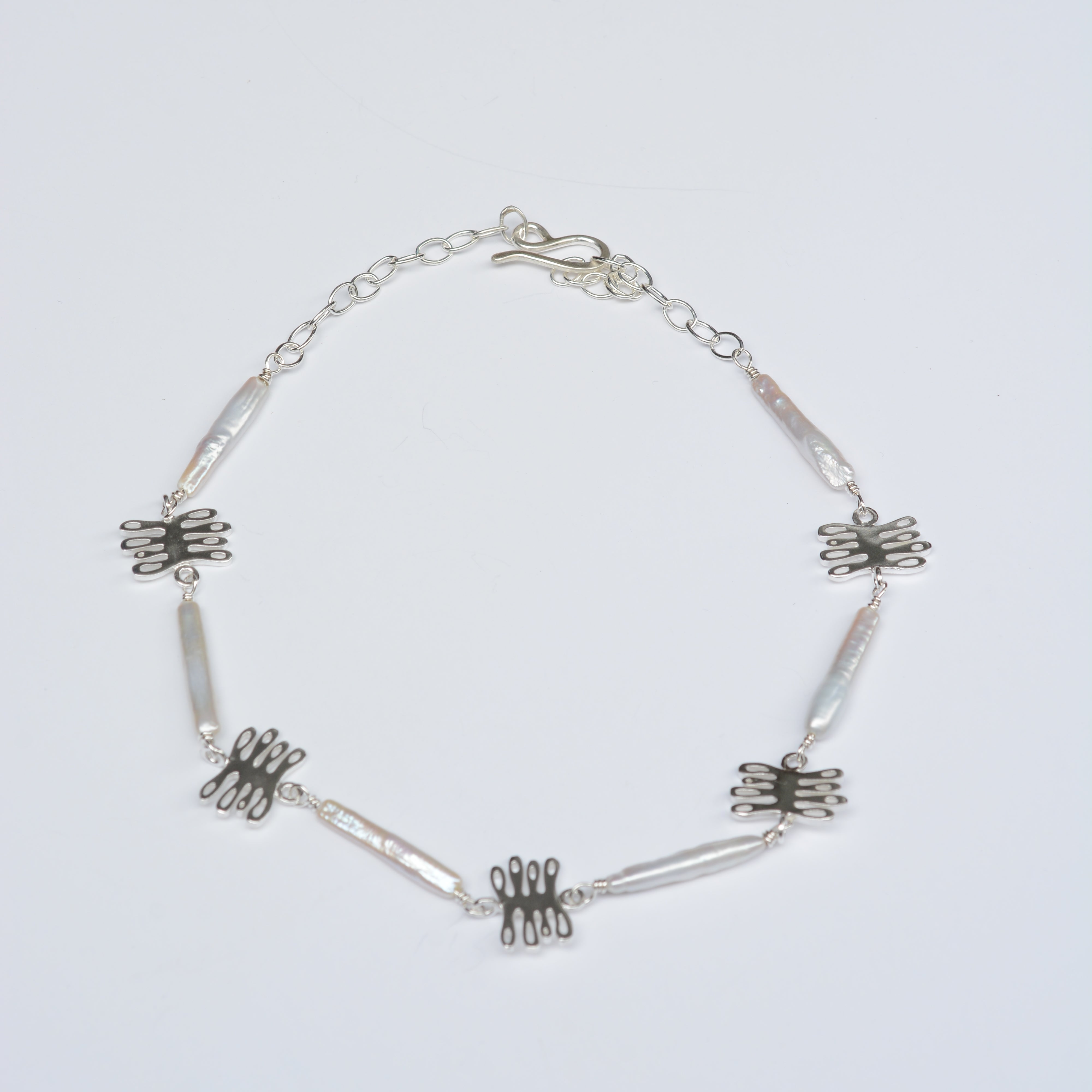Silver necklace with kelp shaped charms and long white pearls