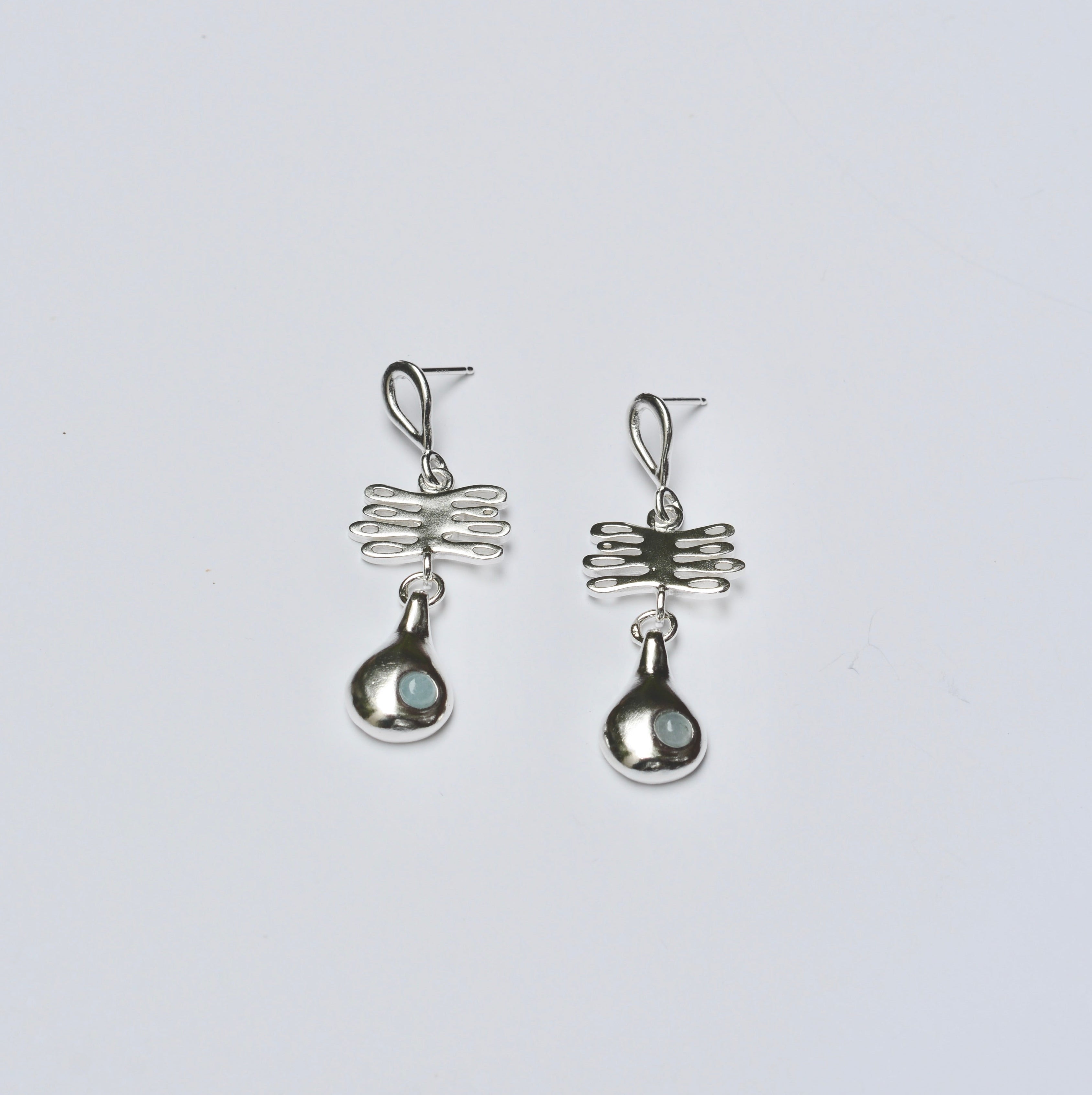 Sterling silver earrings with a plant shaped charm and droplet charm featuring light blue aquamarine stones