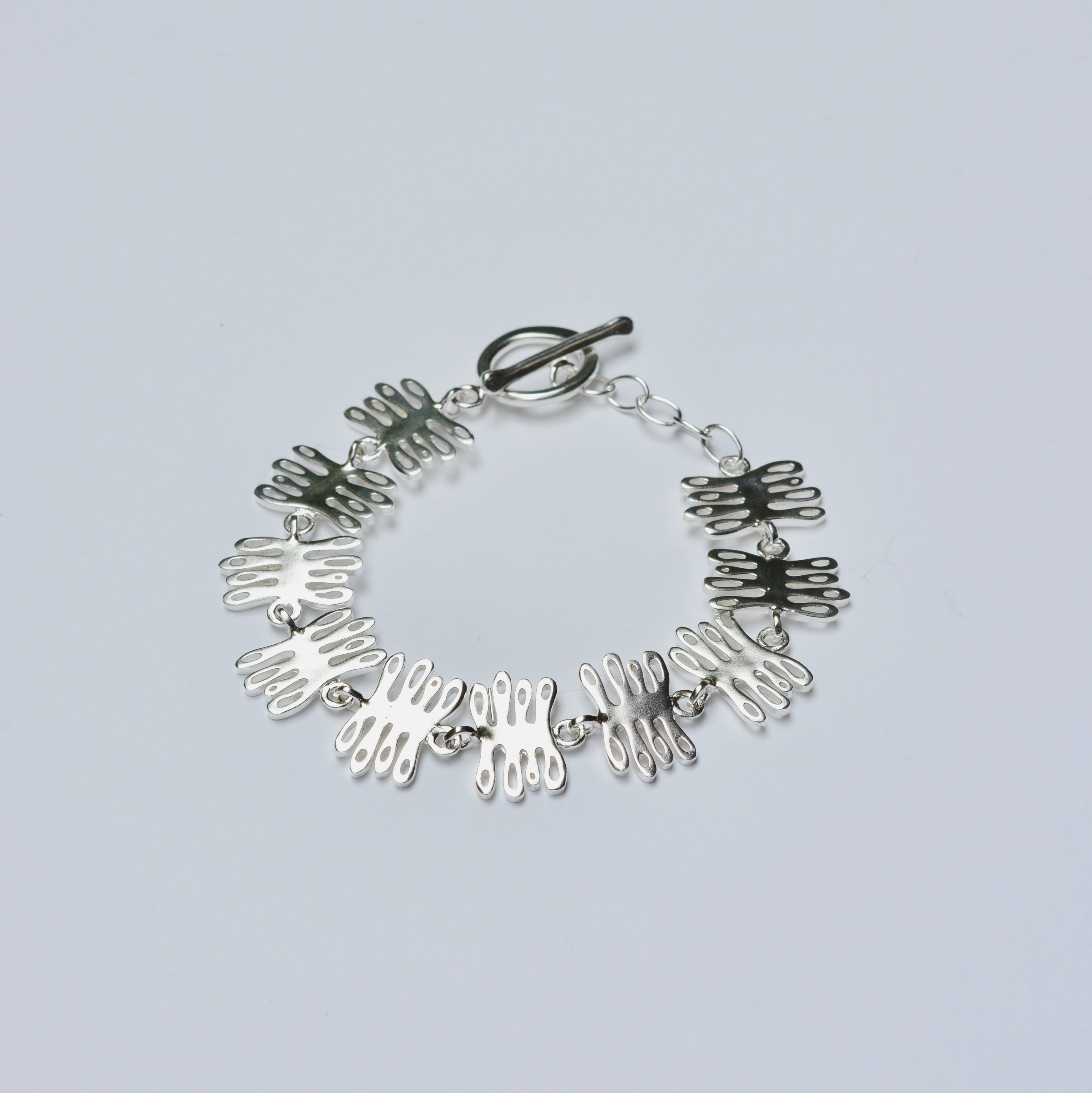 Silver bracelet with coral shaped charms on a light gray background