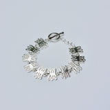Silver bracelet with coral shaped charms on a light gray background