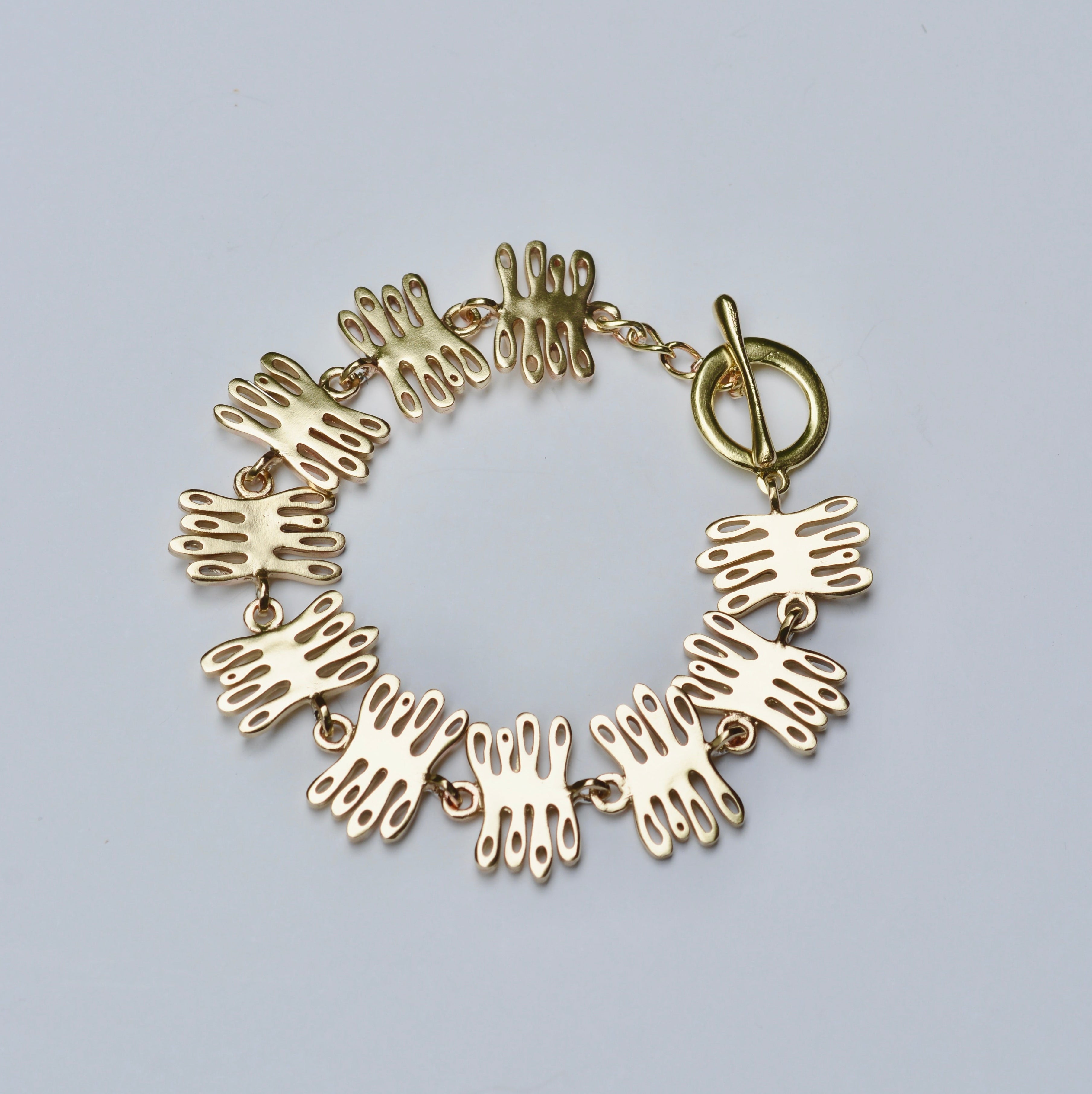 Bronze bracelet with coral-shaped charms on a light gray background