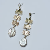 Bronze dangle earrings with kelp shaped charms and pearls on a grey background