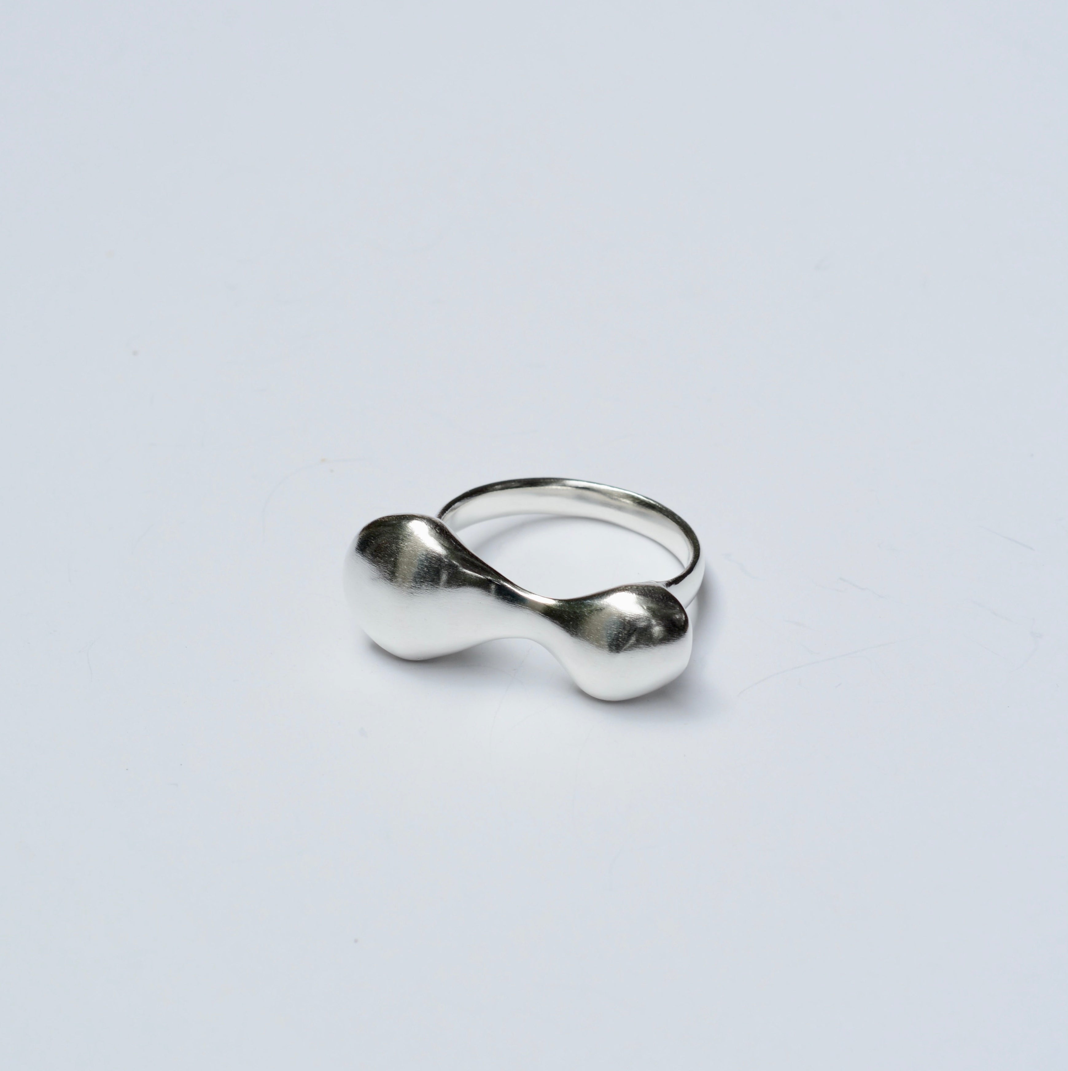 Silver organic shaped ring on a light gray background