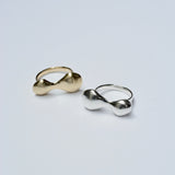 Two rings with organic blobby shapes, one bronze and one silver, on a light gray background