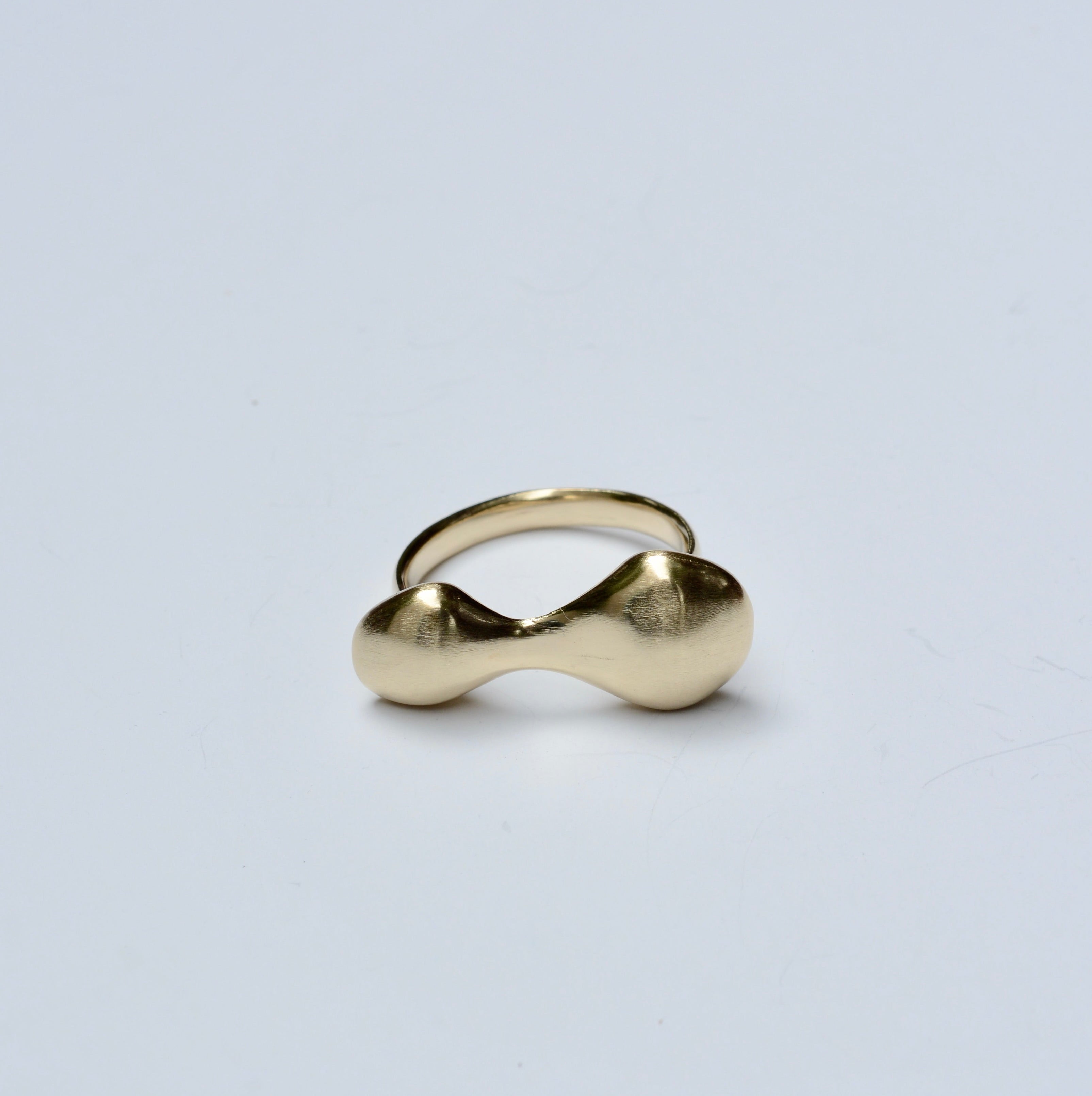 Bronze organic blobby ring on a light gray background