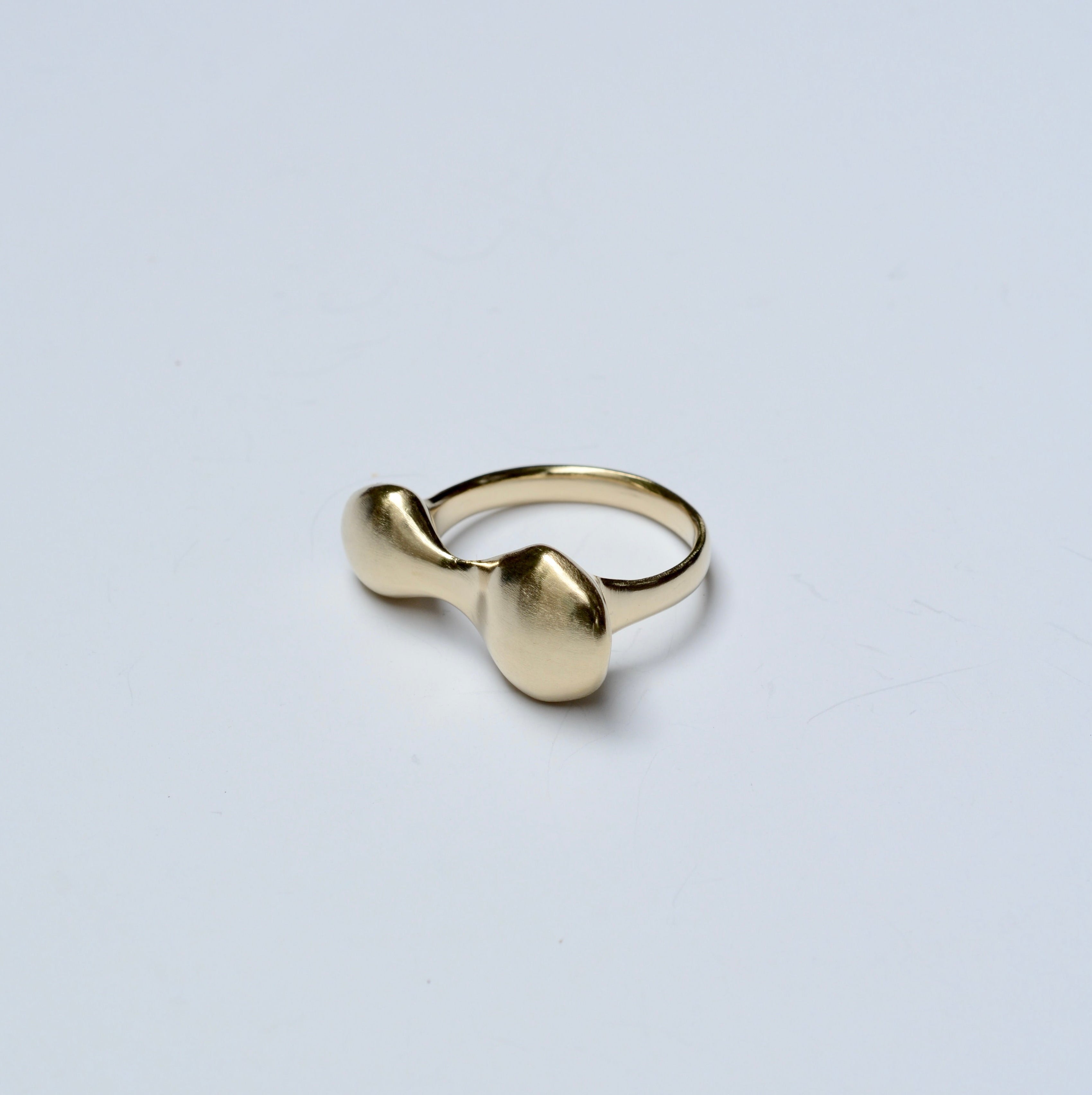 Side view of an organic shaped bronze ring on a grey background