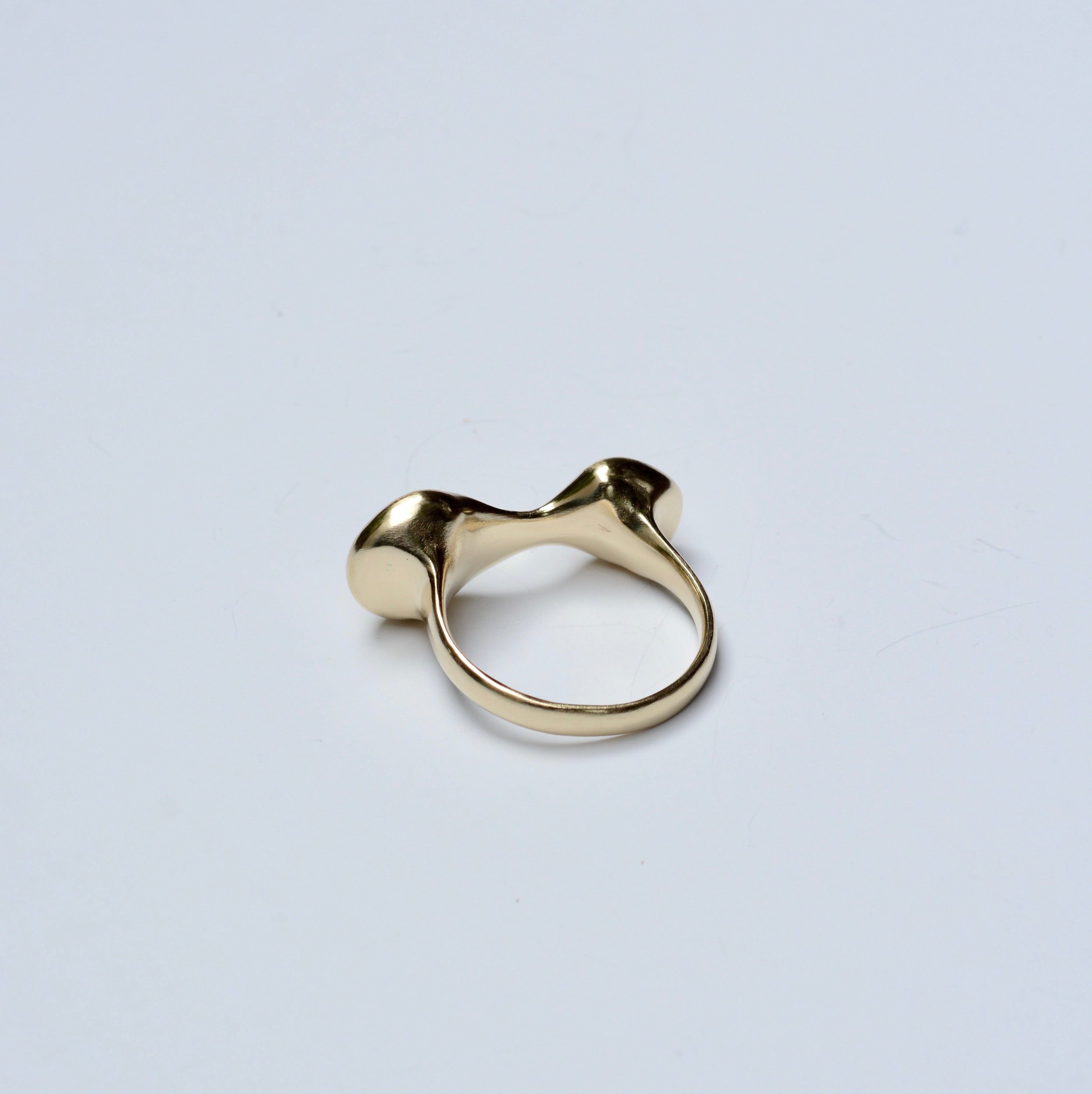Back view of a bronze ring with an organic shape on a grey background