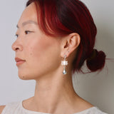 Woman with red hair wearing a silver earring against a plain background