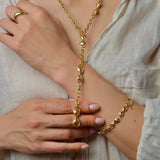 Person wearing a bronze chain necklace and bracelet, with a neutral background
