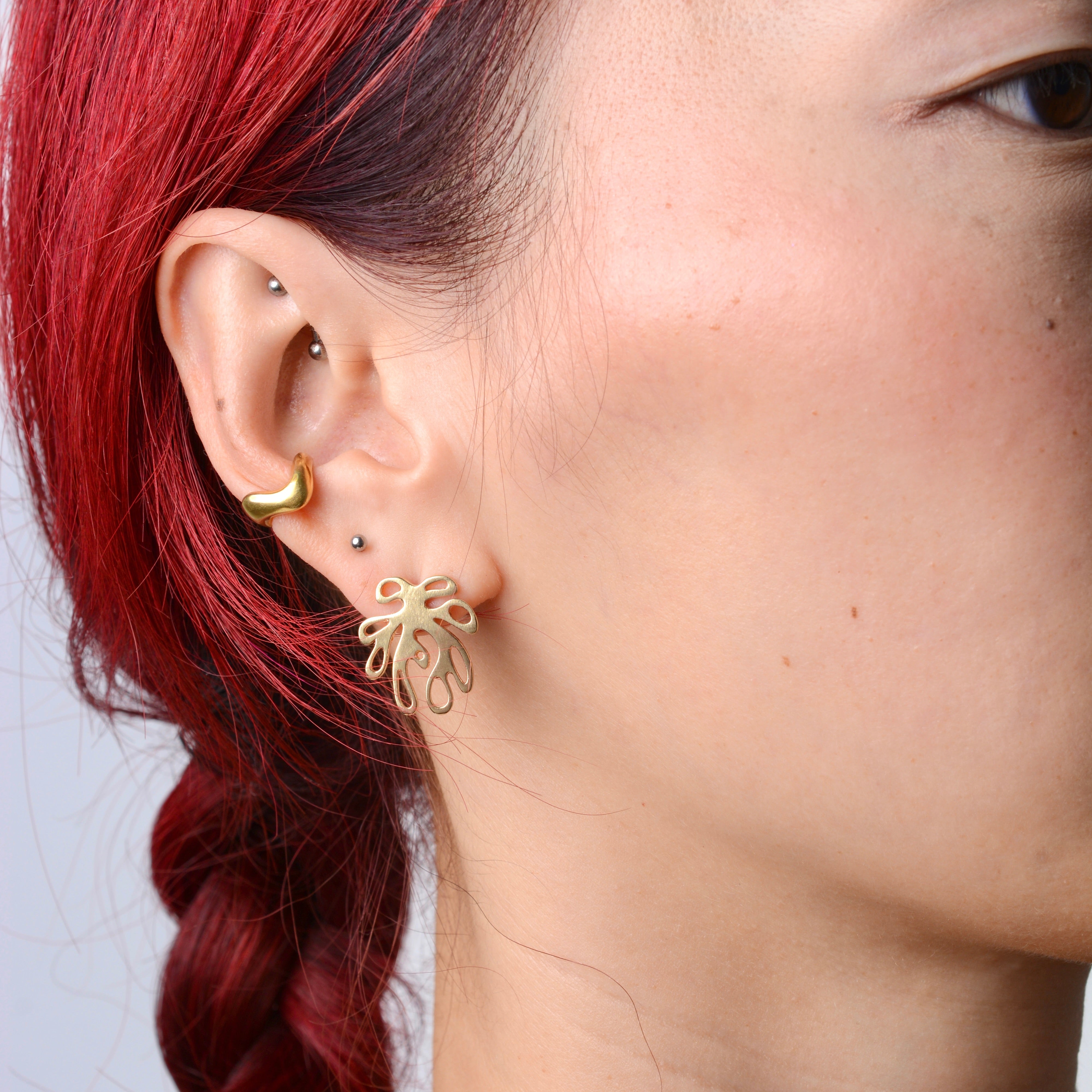 Close-up of a person wearing bronze wavy ear cuff and coral shaped bronze earring. 