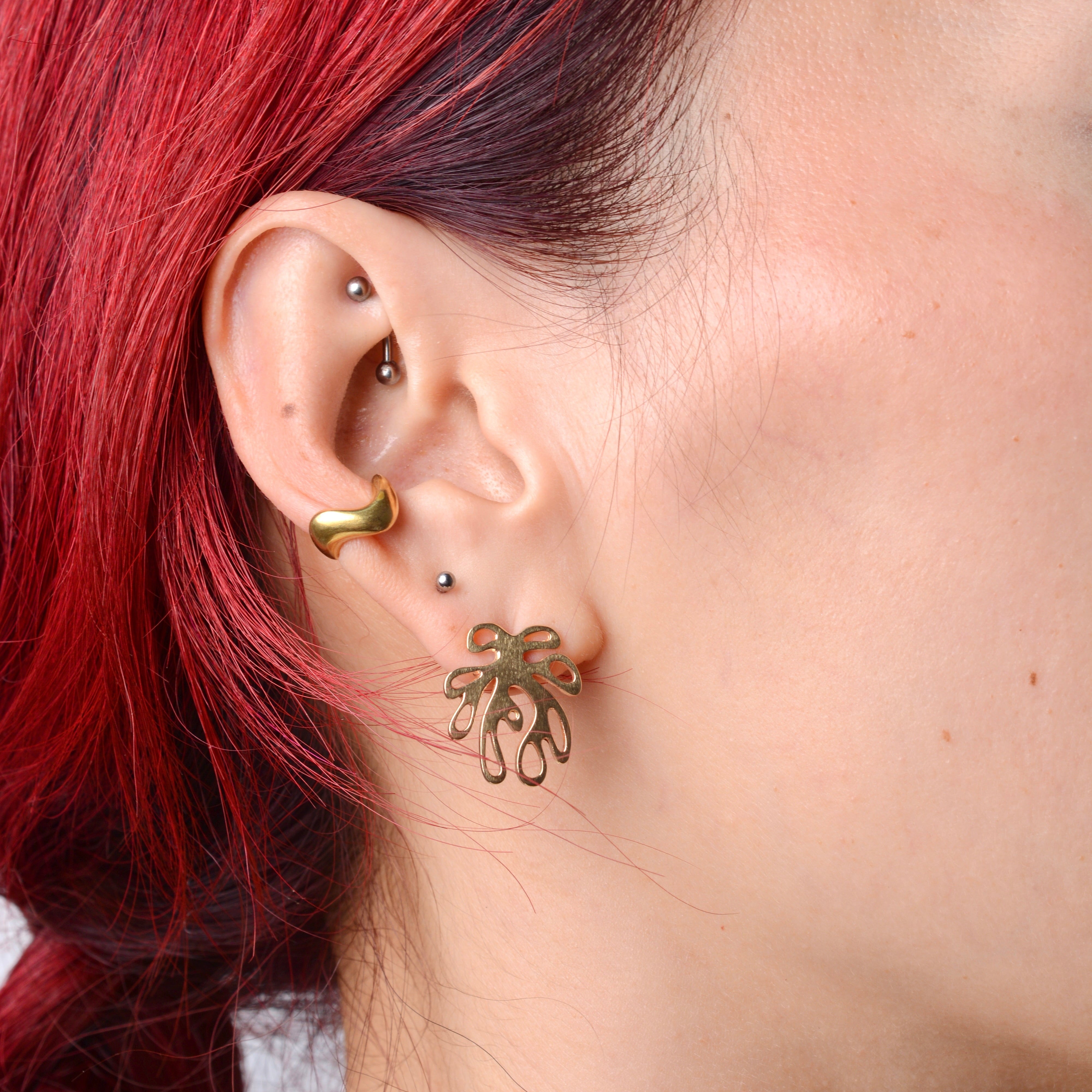 woman wearing a bronze wavy ear cuff and post of a coral shaped bronze earring.