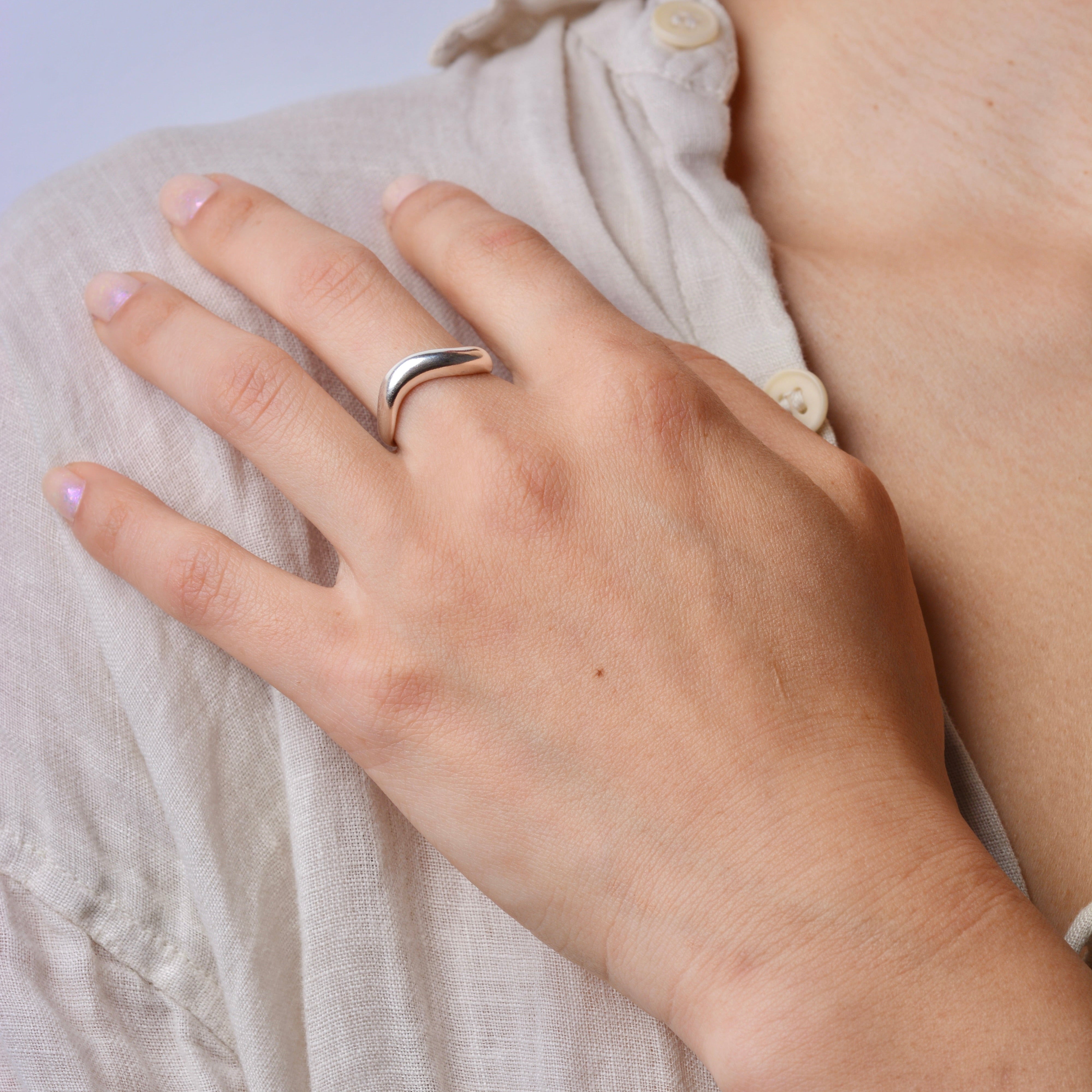Close-up of a hand wearing a silver ring on a light fabric background