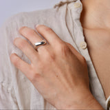 Close-up of a hand wearing a wide wavy silver ring on a shoulder