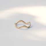 Thin wavy gold band sitting on a white background