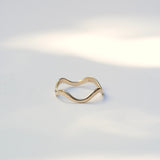 Thin 14k yellow gold ring with wavy curves sitting on a white background