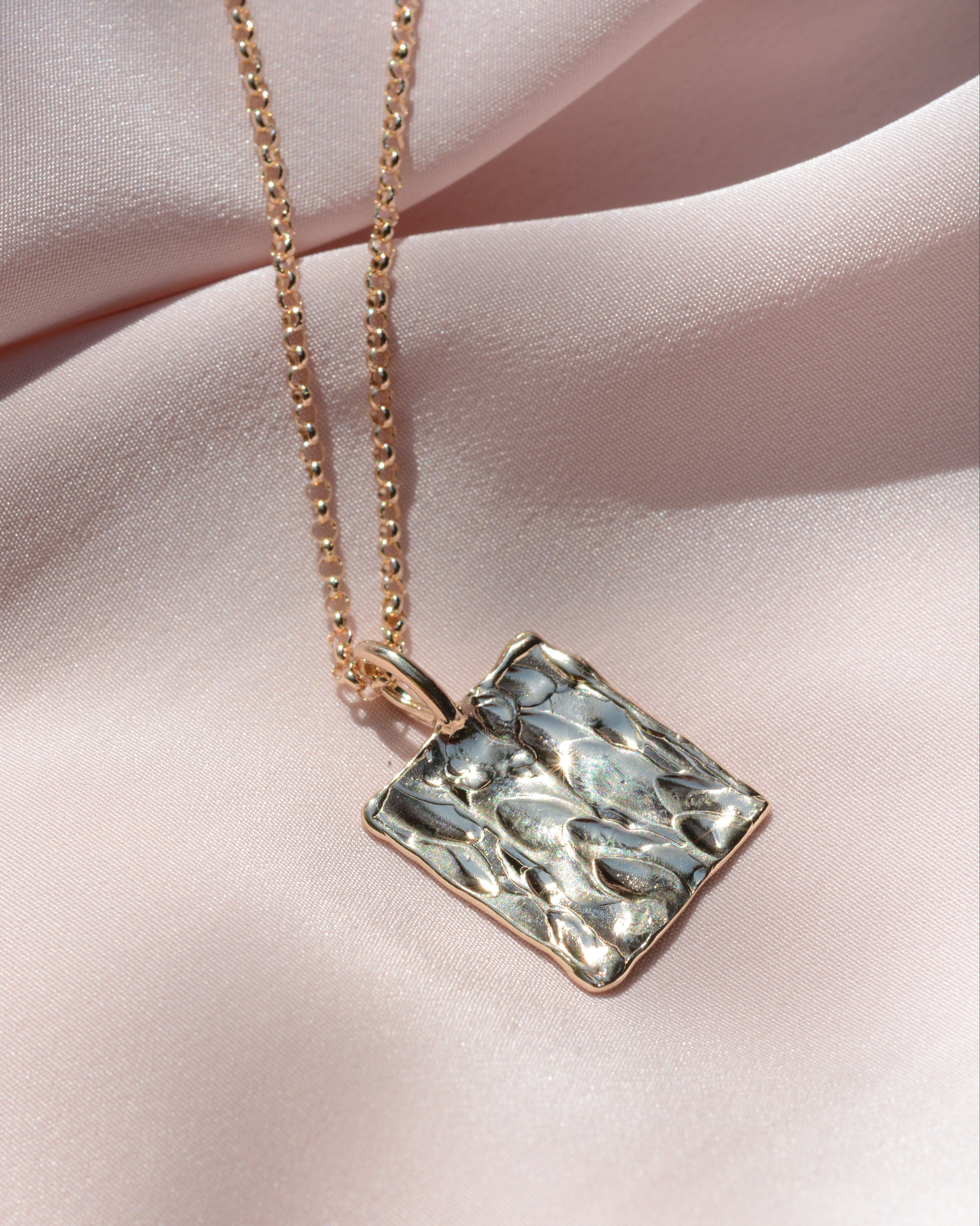 Gold rectangular textured pendant on a chain 