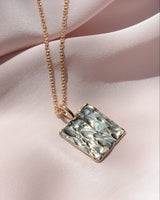 Gold rectangular textured pendant on a chain 