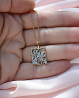 Hand holding a rectangular pendant with organic bark like texture