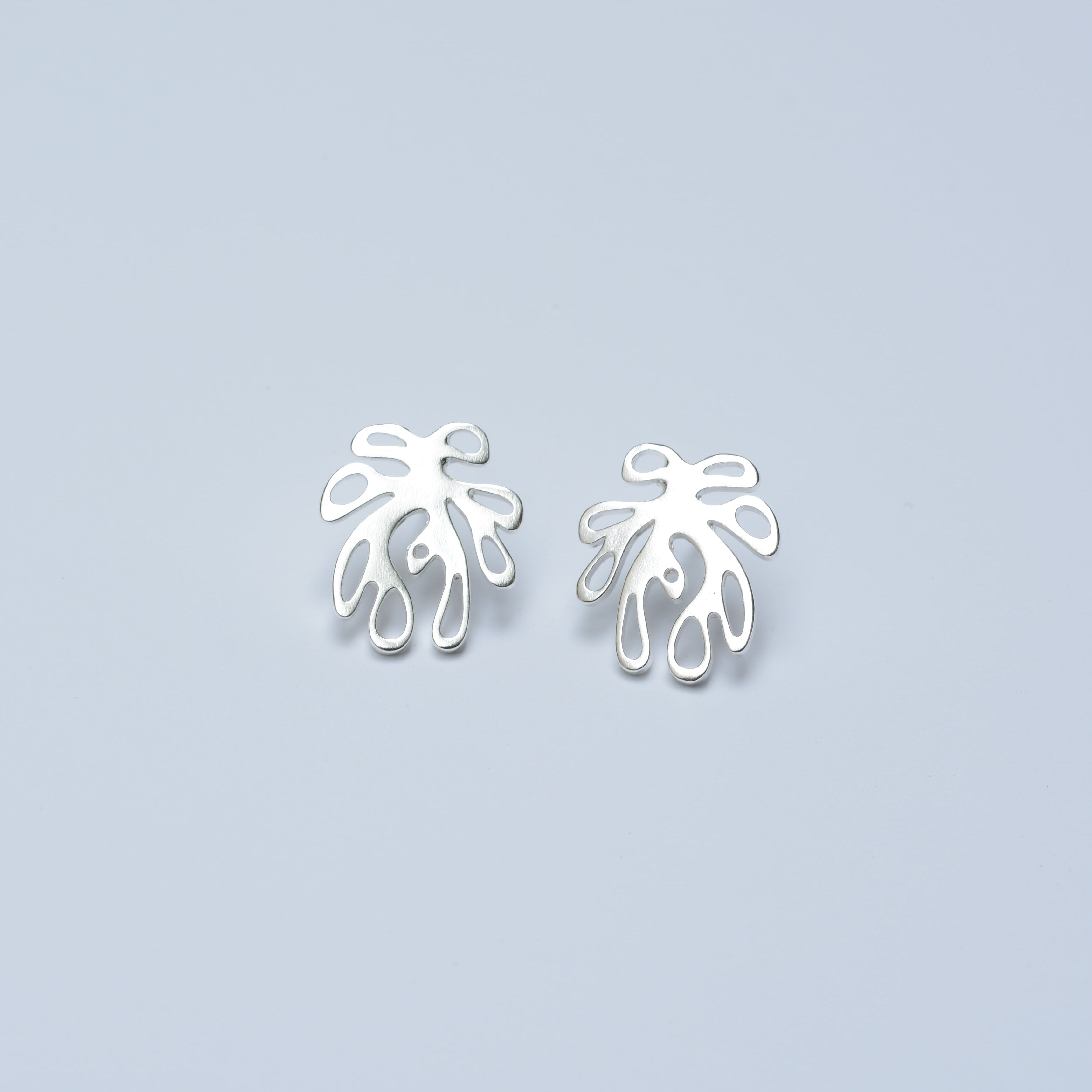 Pair of silver leaf-shaped earrings on a light blue background