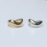 Two bronze and silver organic wavy rings on a light gray background