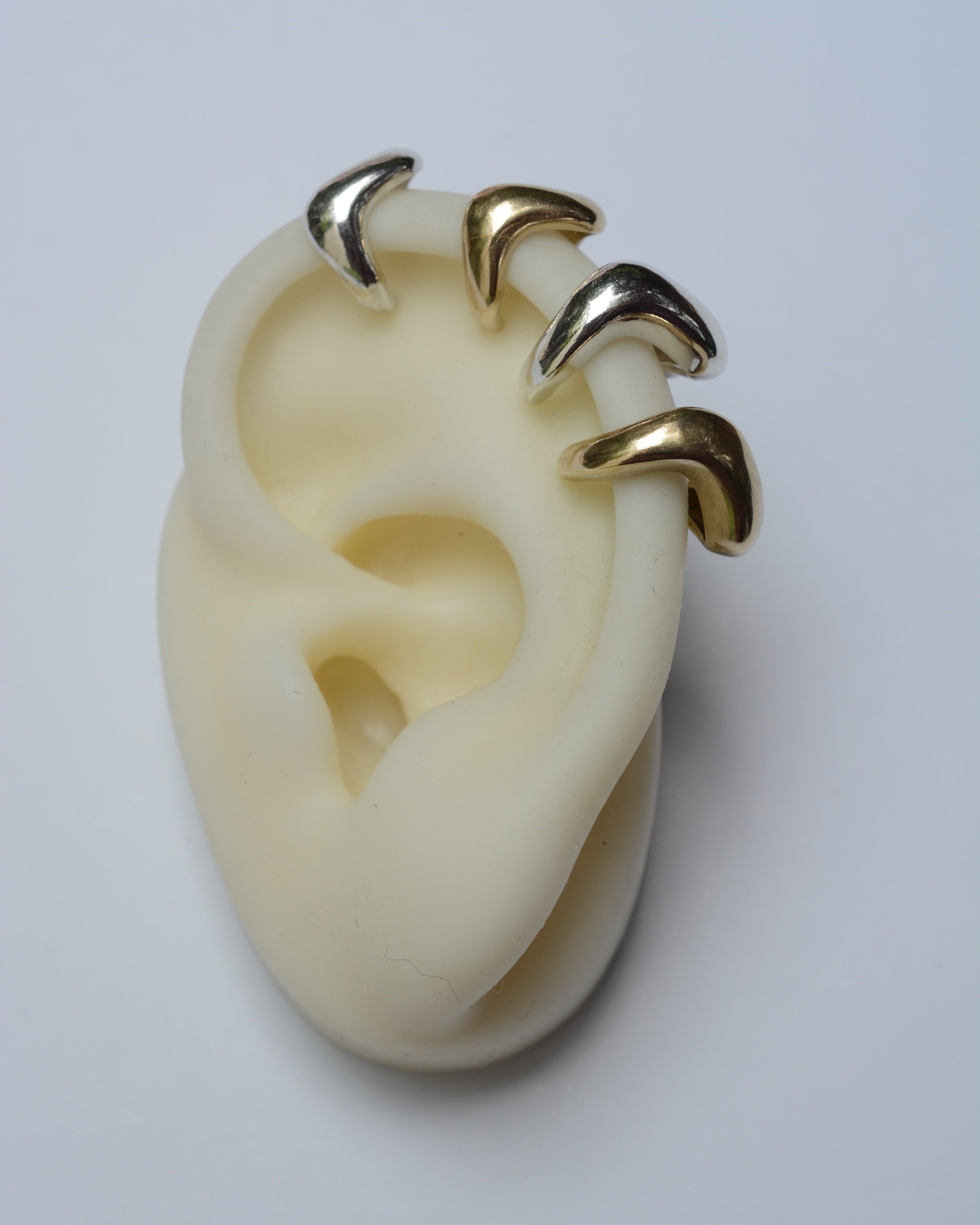 Gold and silver ear cuff on a white ear model