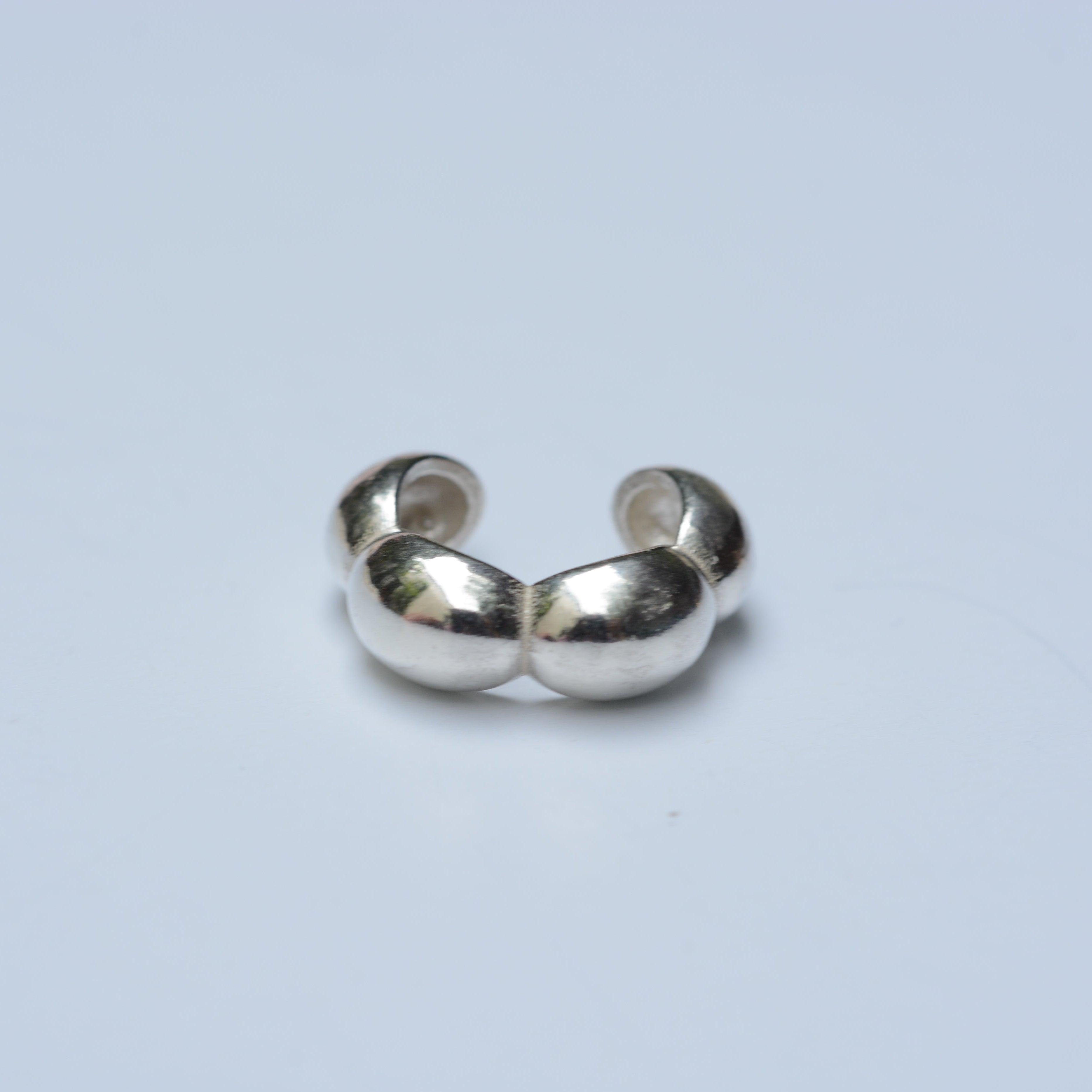 Silver ear cuff with a bubble shape on a grey background