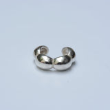 Silver ear cuff with a bubble shape on a grey background