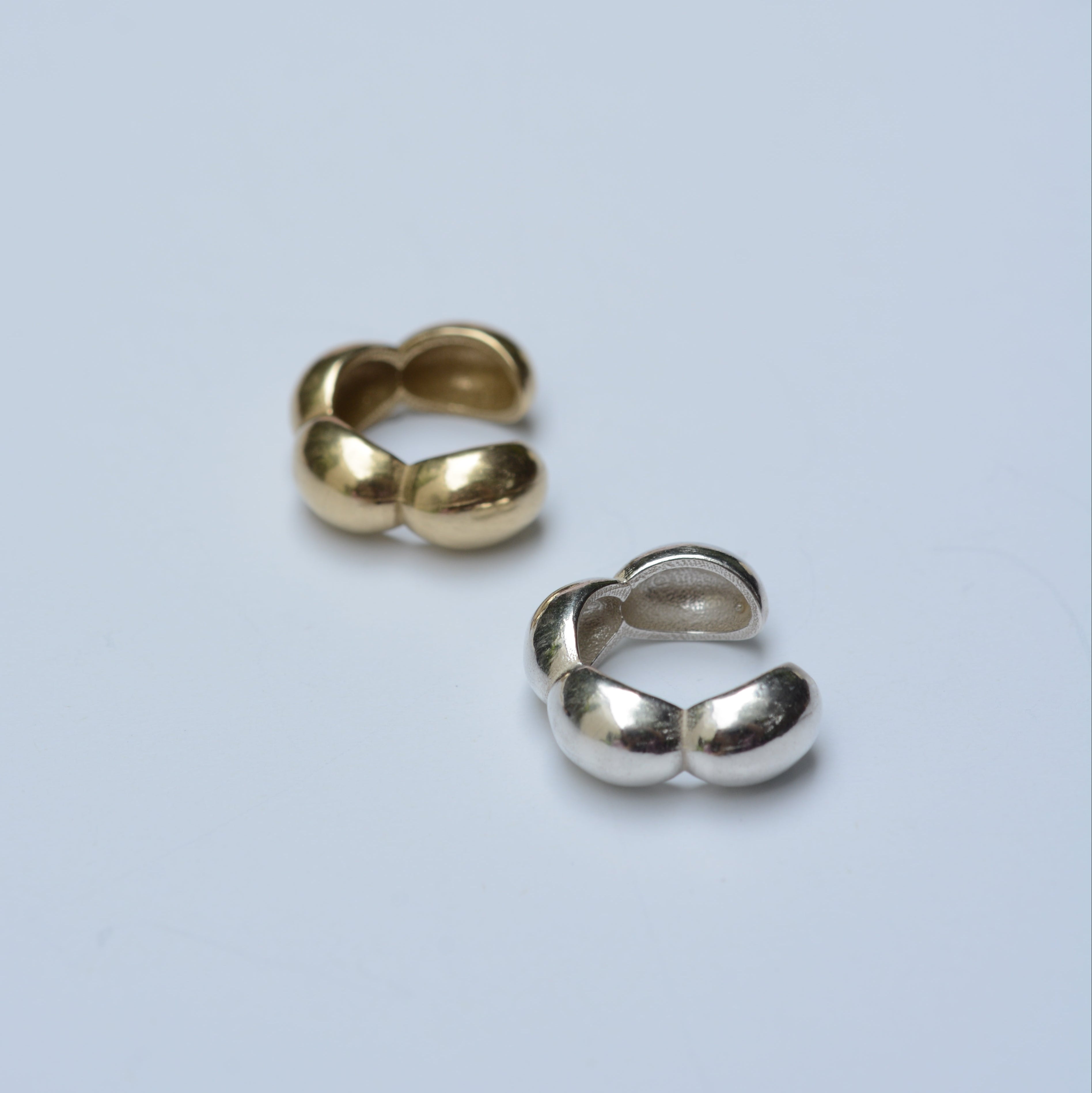 Bubble ear cuffs in silver and bronze on a grey background