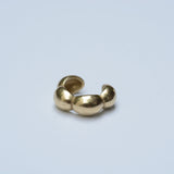 Bronze ear cuff with a bubble shape on a grey background