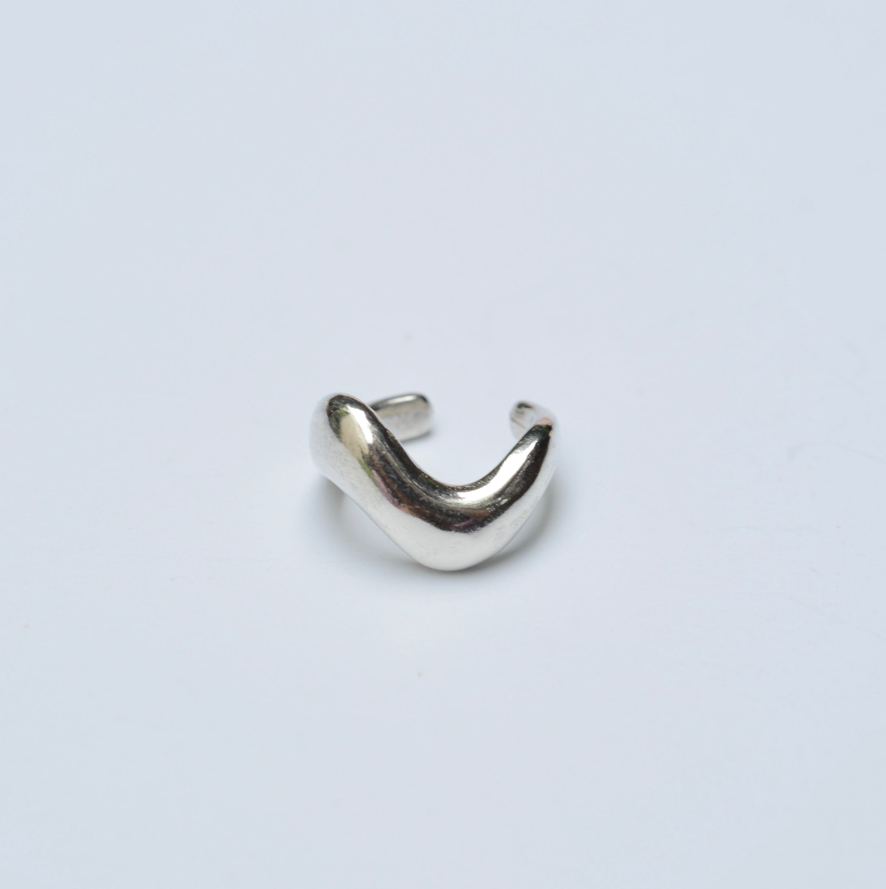 Silver wavy ear cuff on a grey background